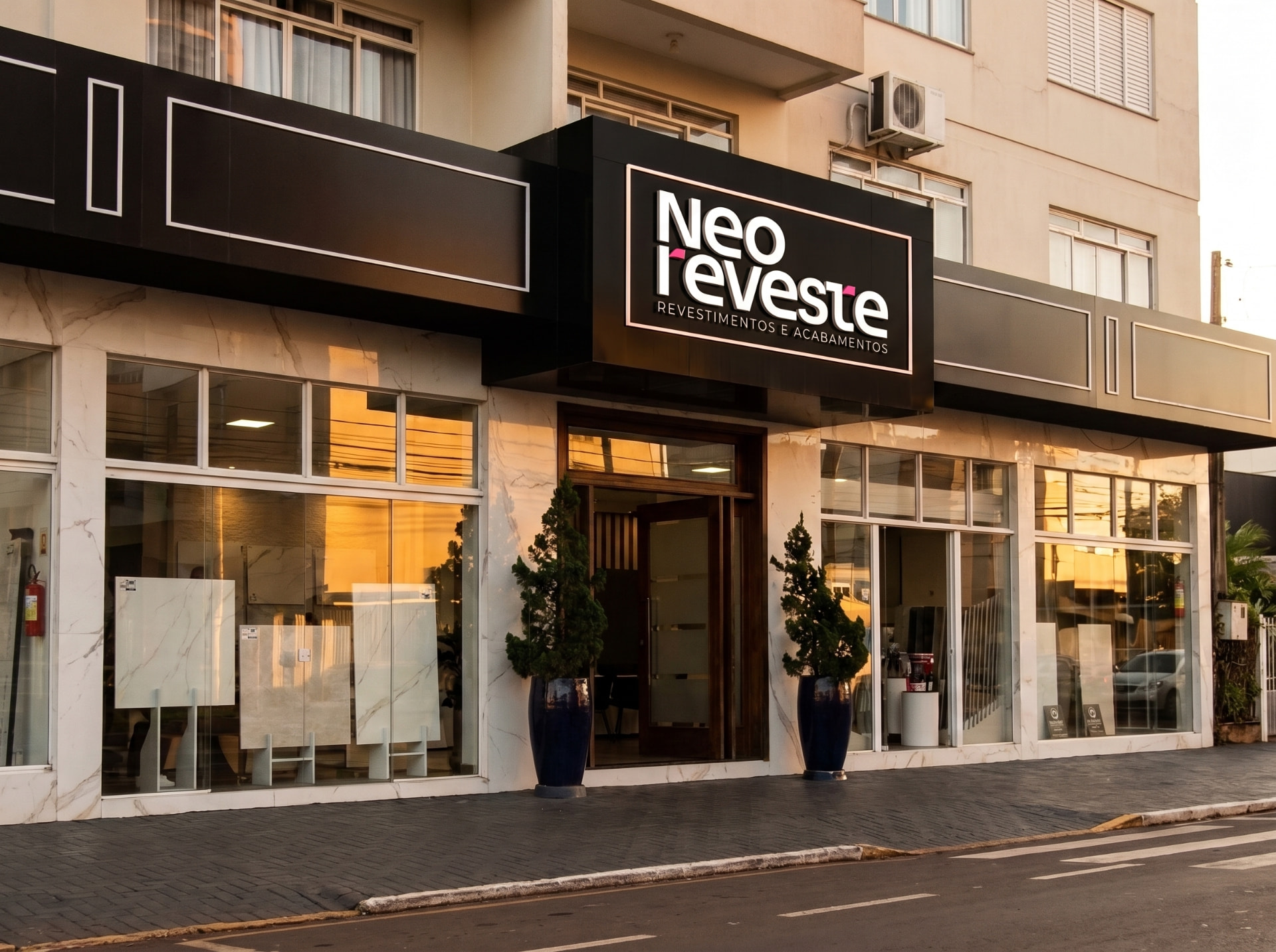 Fachada da loja Neo Reveste em Toledo, com letreiro iluminado e vitrines expondo placas de porcelanato